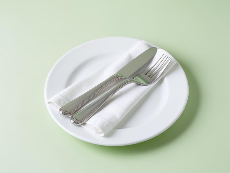 Prato branco com talheres sobre fundo verde claro